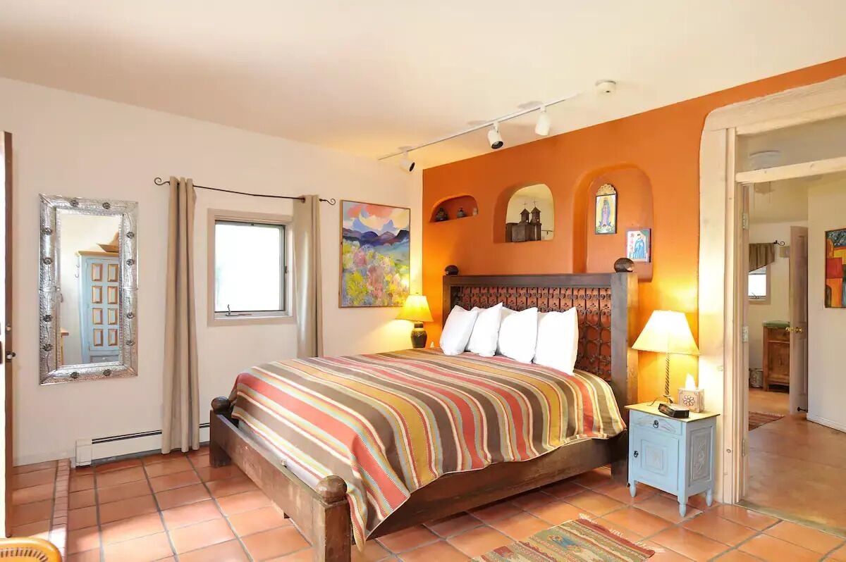 A bedroom with a large bed, a nightstand, a mirror, and a window.