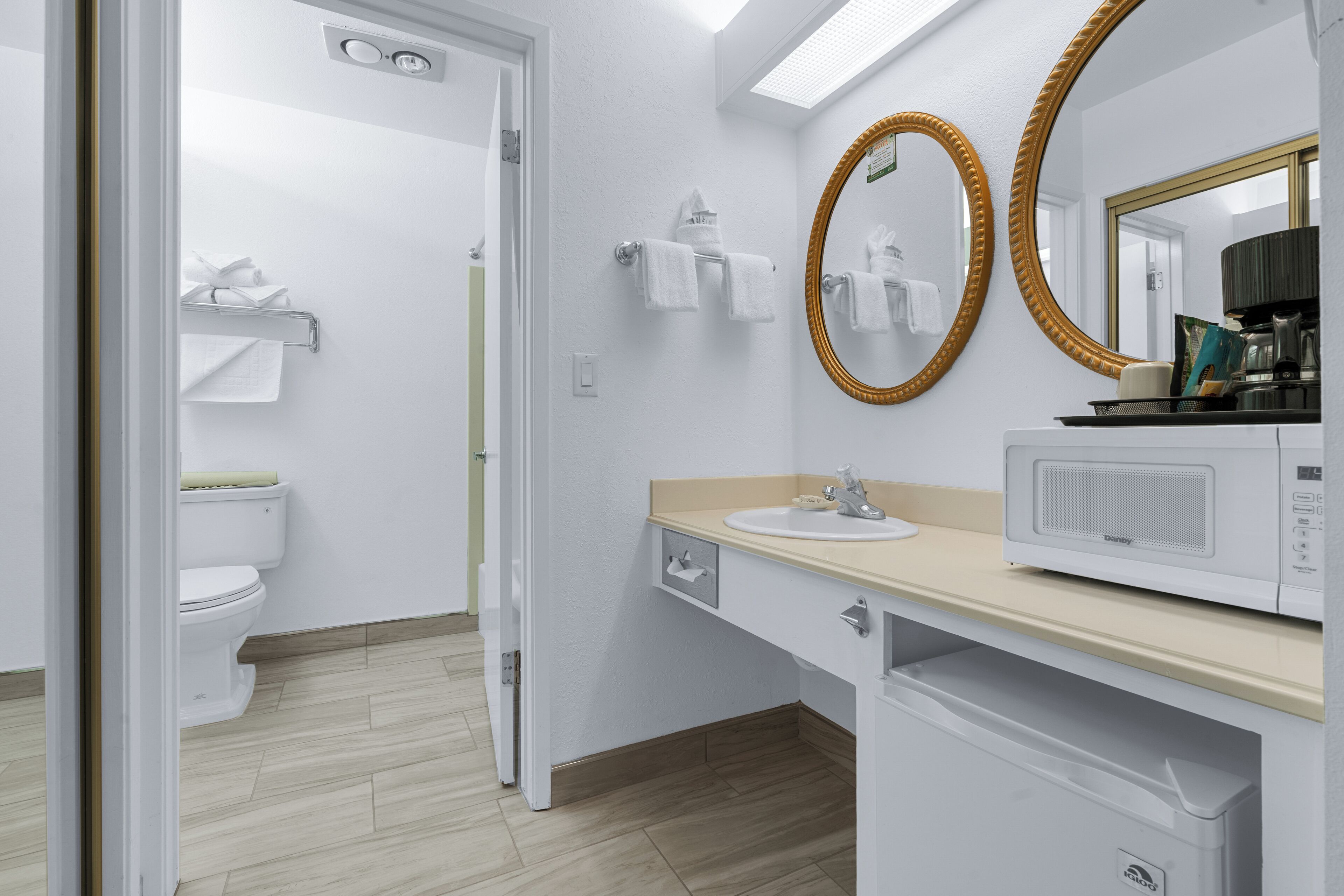 Une salle de bain moderne équipée de toilettes, d’un lavabo et d’un four à micro-ondes posé sur le comptoir.