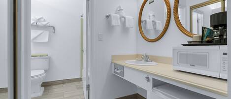 Une salle de bain moderne équipée de toilettes, d’un lavabo et d’un four à micro-ondes posé sur le comptoir.
