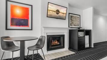 Una habitación moderna con chimenea, una mesa redonda, dos sillas y obras de arte en las paredes.