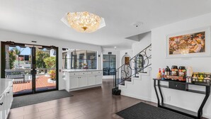 Una cocina moderna con una isla grande, una escalera con barandilla de hierro forjado y una estación de café con café recién hecho y pasteles.