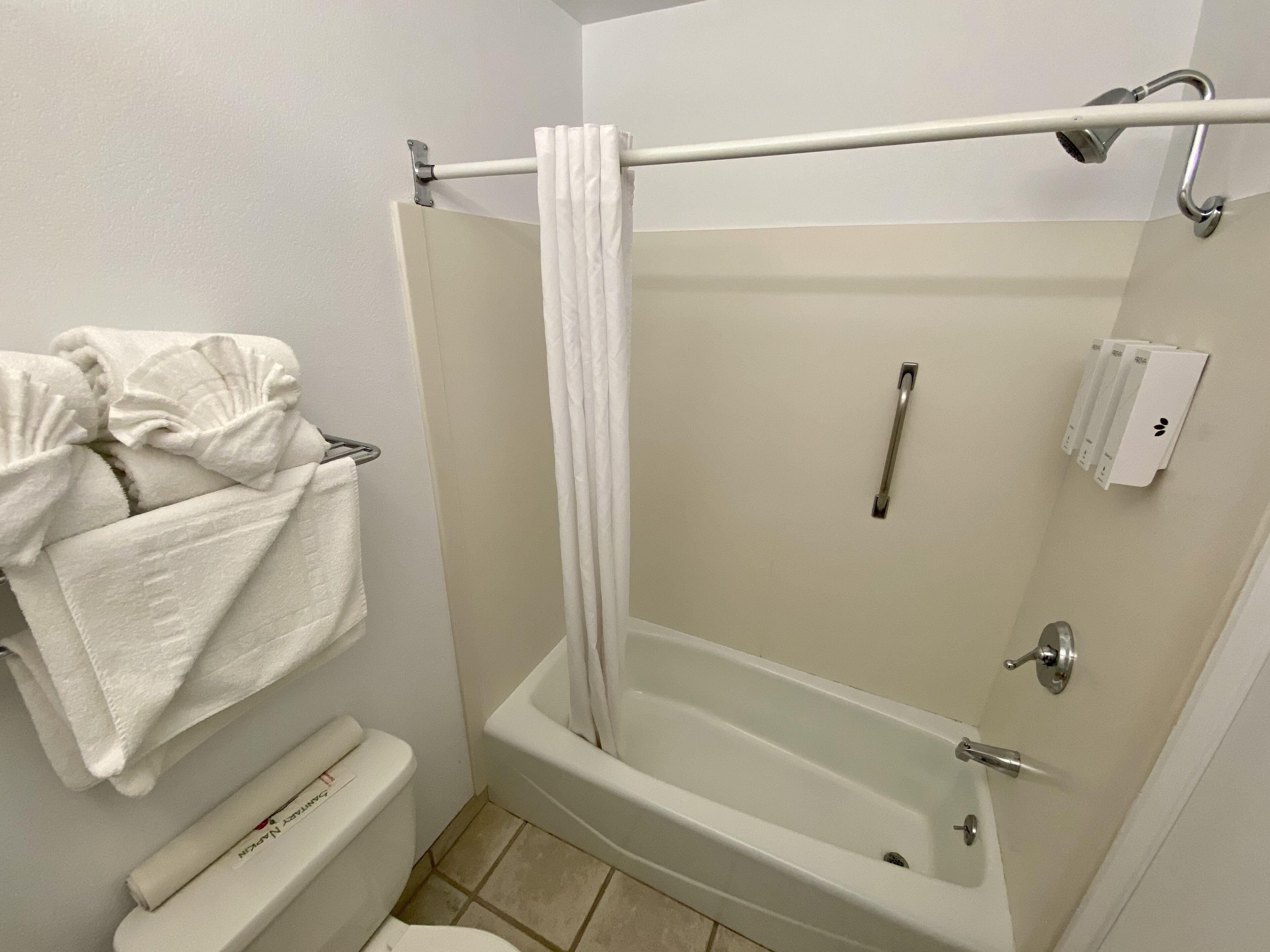 A bathroom with a bathtub, a toilet, a towel rack, and a shower curtain rod.