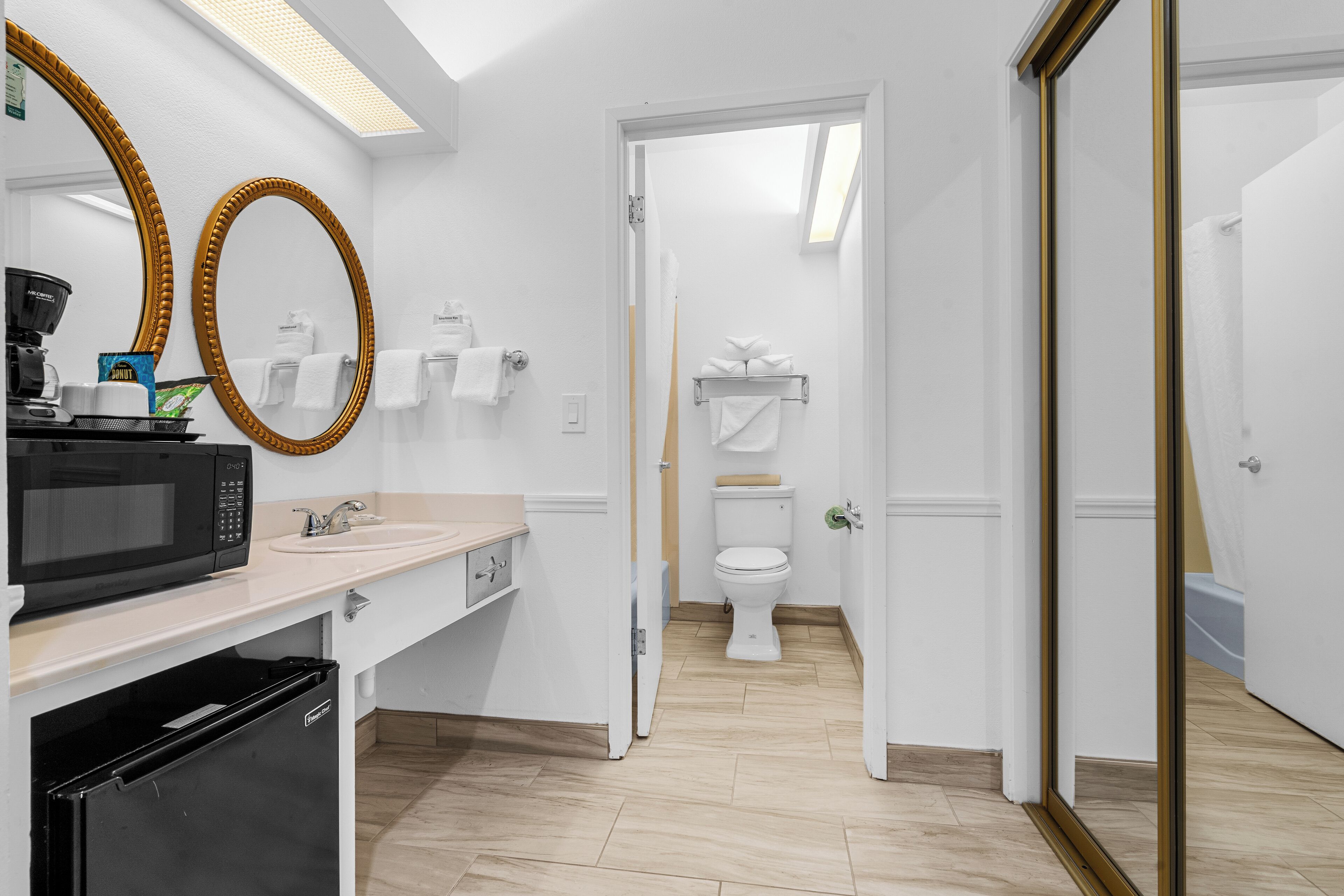 A modern bathroom with a white sink, a black microwave, and a toilet.