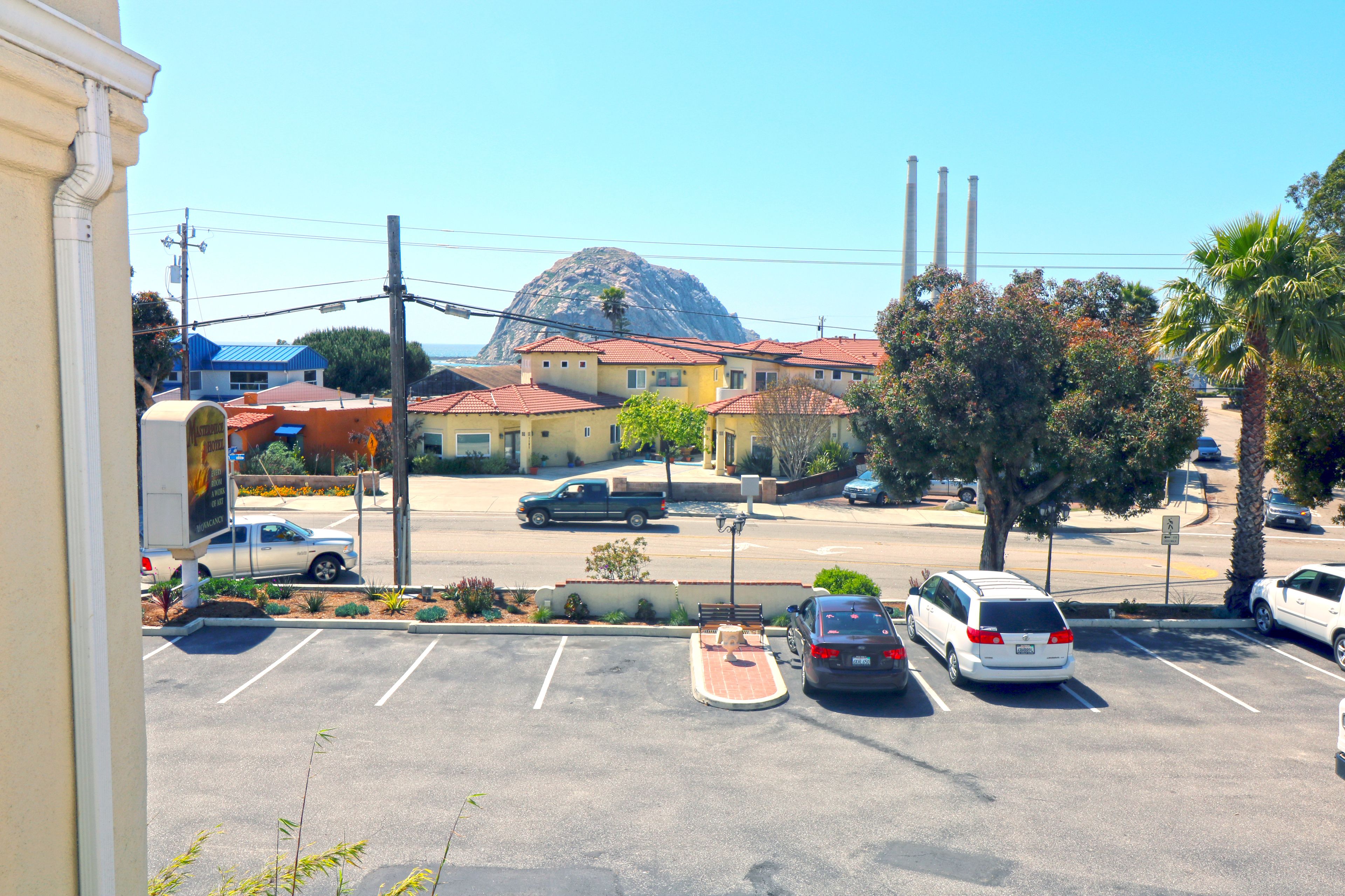 A parking lot with several cars and a building with a red roof in the background.