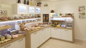Un bufé de desayuno con diferentes opciones de comida, una máquina de café y una presentación de frutas.