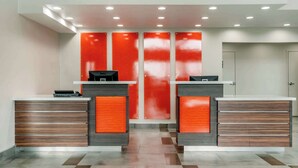 A reception area with a modern design, featuring a central desk with a computer and a small printer, flanked by two cabinets with drawers.