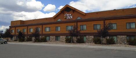 A C'mon Inn hotel building with a flat roof, multiple windows, and a parking lot in front.