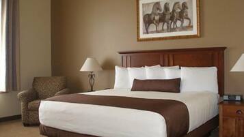 A hotel room with a large bed, a chair, a nightstand, and a framed picture on the wall.