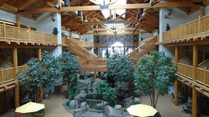 A spacious indoor area with wooden beams, multiple levels, and a central rock garden.