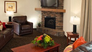 A living room with a fireplace, leather furniture, and a mounted TV.