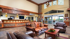 A spacious lobby with leather sofas, a wooden reception desk, and a stone accent wall.