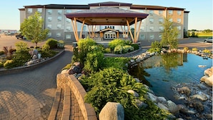 A hotel with a covered entrance, landscaped garden, and a pond.
