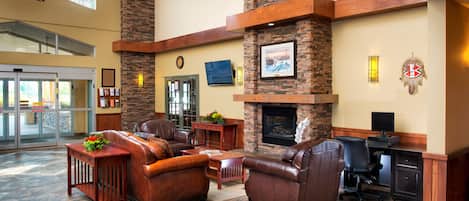 A spacious lobby with leather sofas, a fireplace, and a desk area.