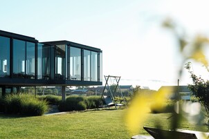 A modern building with large glass windows, a grassy lawn, and a swing set.