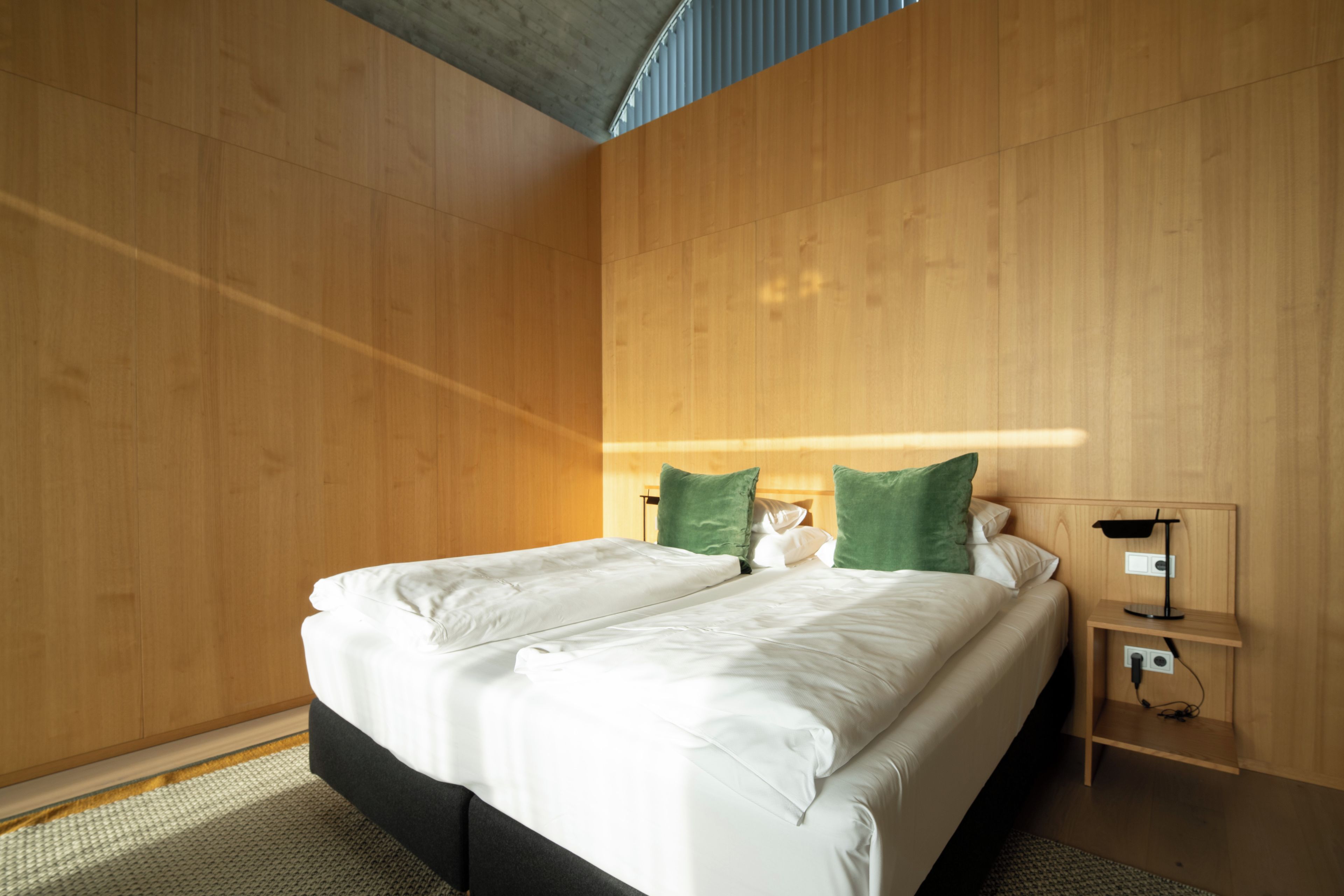 Une chambre à coucher moderne avec un grand lit, des murs en bois et une table de chevet avec une lampe.