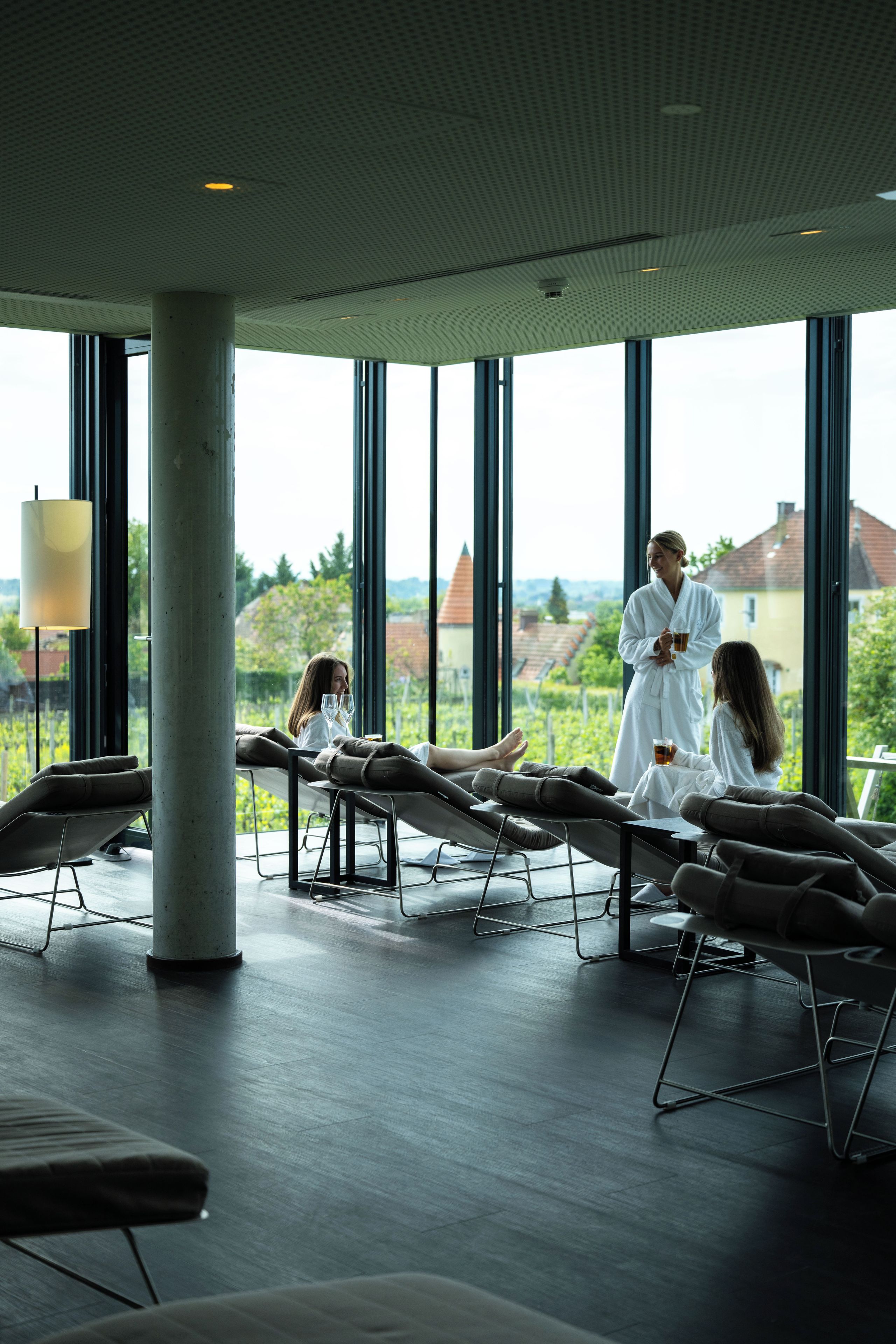 A modern spa room with large windows, reclining chairs, and a view of the cityscape.