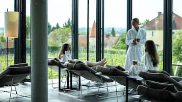A modern spa room with large windows, reclining chairs, and a view of the cityscape.