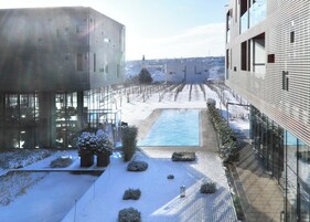 Un edificio moderno con fachada de vidrio, una piscina y terreno cubierto de nieve.