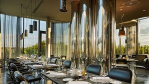 Un espace de restauration moderne avec de longues tables, des chaises noires et des luminaires suspendus.