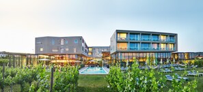 A modern hotel with a pool, outdoor seating, and a well-maintained garden.