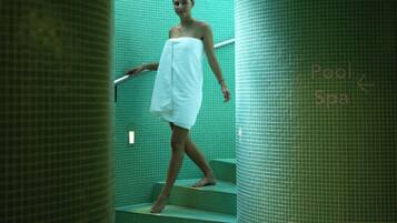A person descending a green-tiled staircase in a spa-like setting with a sign indicating a pool and spa area.