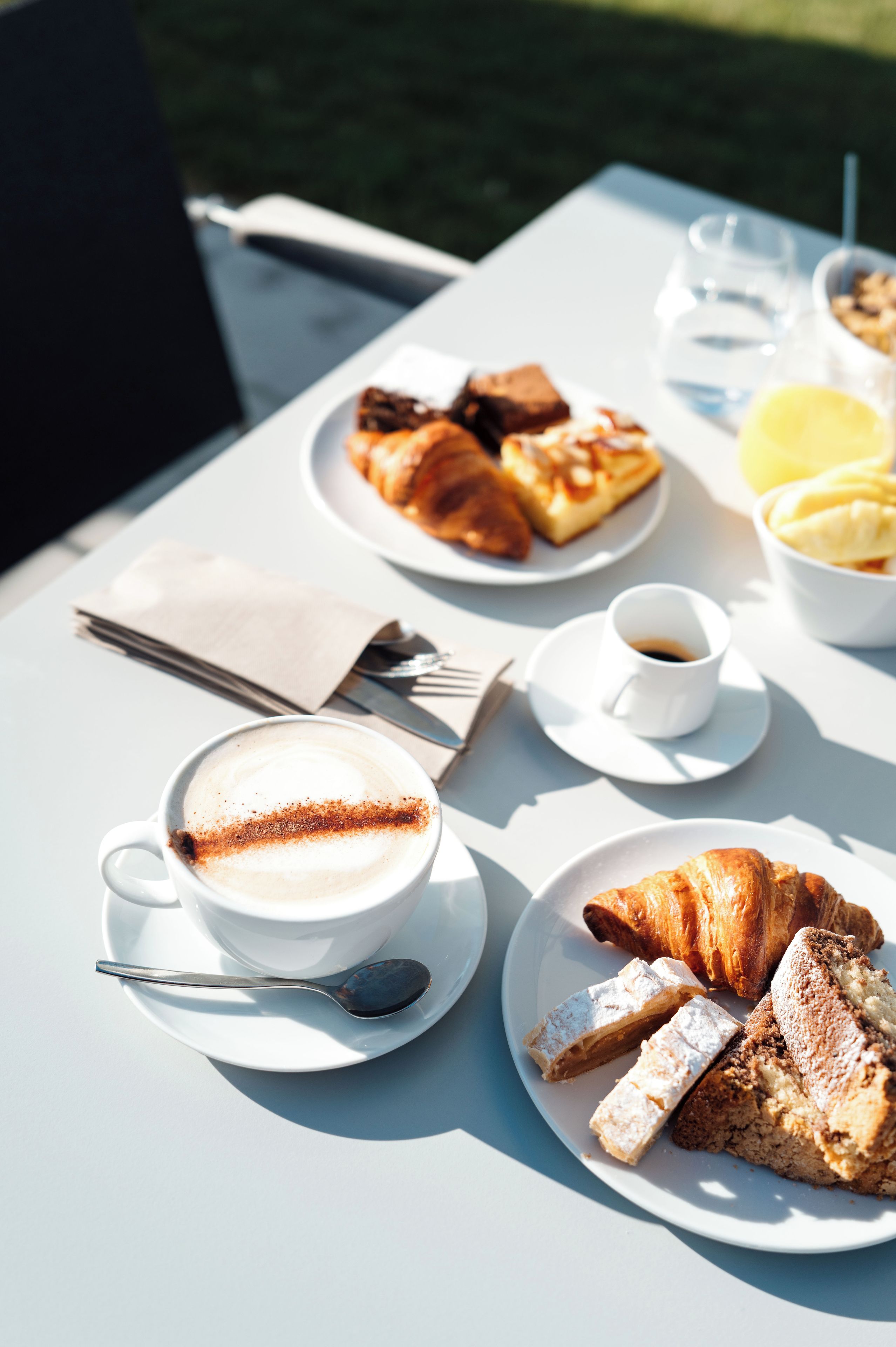 Une table dressée avec une tasse de café, un croissant et une assiette de pâtisseries.