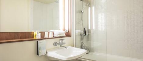 A bathroom with a white sink, a mirror, and a glass-enclosed shower.