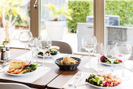 A dining table set with plates of food, wine glasses, and cutlery.