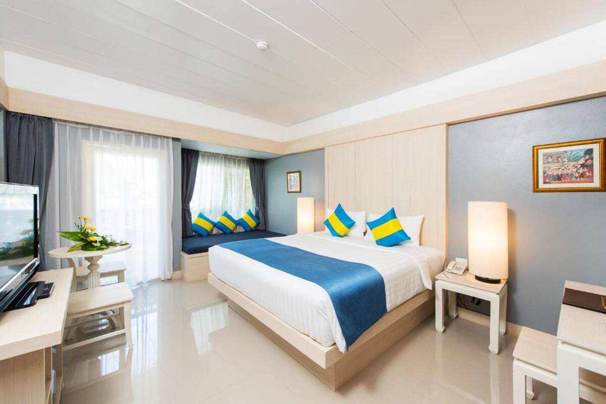 A modern hotel room with a large bed, bedside tables, a desk, and a TV.