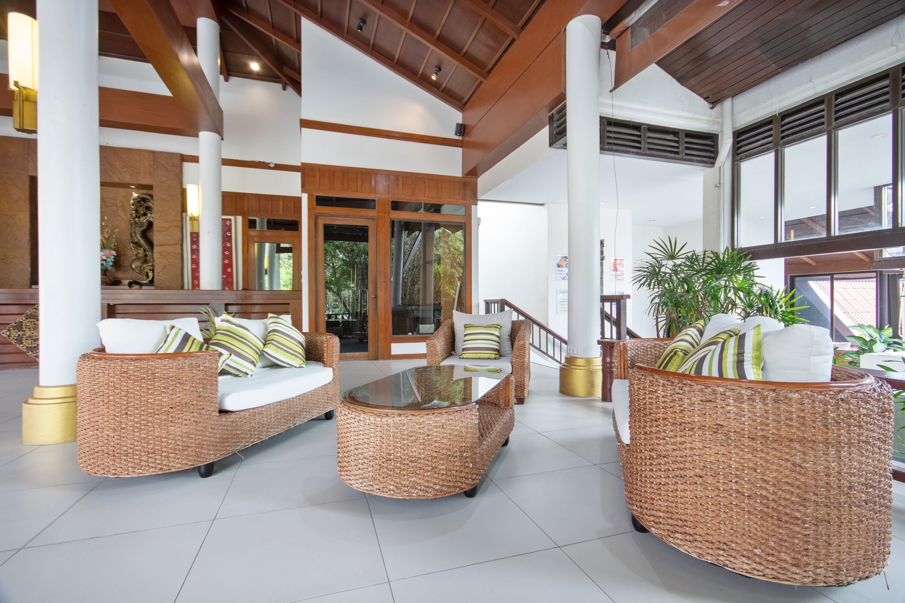 A spacious lobby with wicker furniture, a glass coffee table, and a staircase leading to another area.