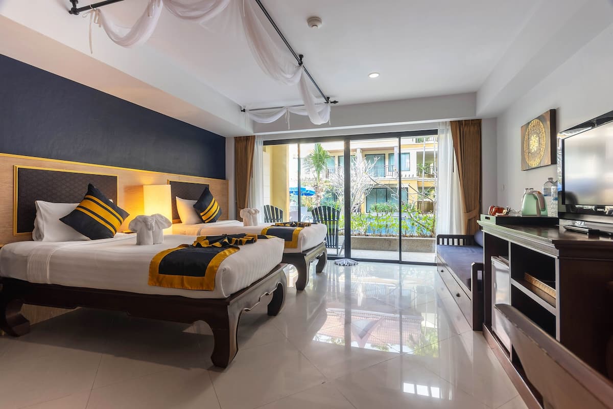 A hotel room with a large bed, a smaller bed, a desk, and a view of the outdoors.