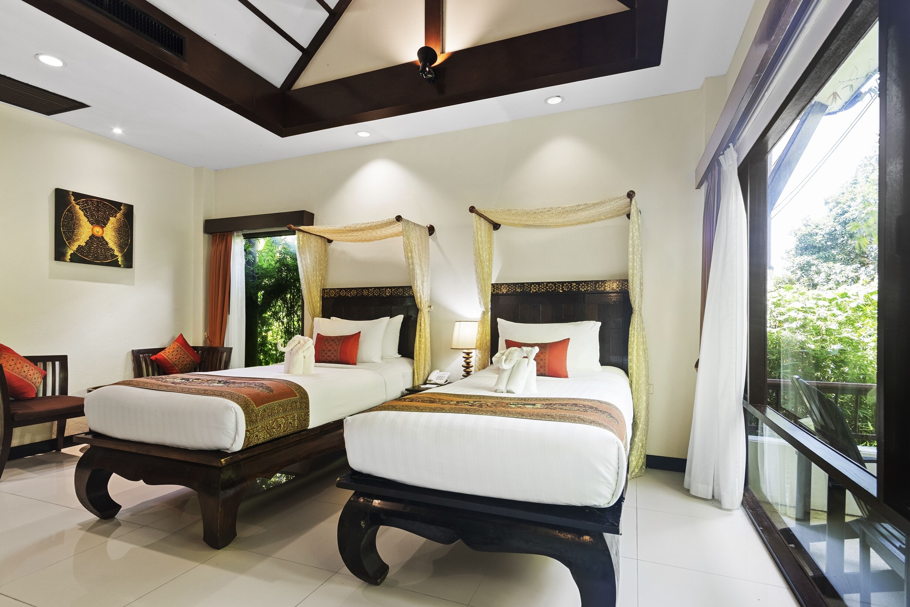 A hotel room with two beds, a large window, and a ceiling fan.