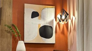 Camera da letto con un letto, una sedia, una scrivania, un quadro e una lampada a sospensione.