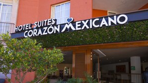 Esterno dell'Hotel Suites Corazon Mexicano, con facciata rossa, grandi piante in vaso e ingresso ben visibile.