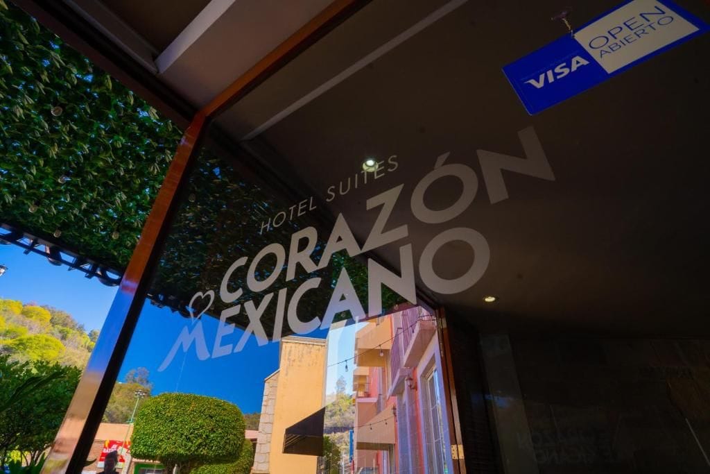 L’entrée d’un hôtel, avec une enseigne indiquant « Hotel Suites Corazon Mexicano » et un logo Visa signalant l’acceptation des paiements par carte Visa.