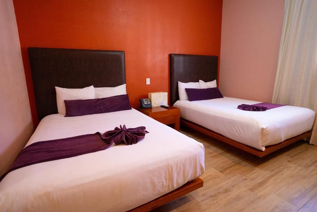 Two beds with headboards, a nightstand with a phone, and a wooden floor.