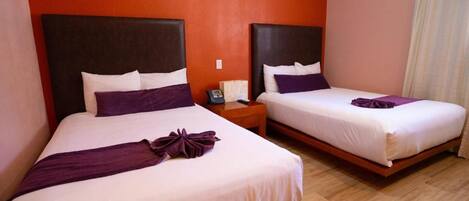 Two beds with headboards, a nightstand with a phone, and a wooden floor.