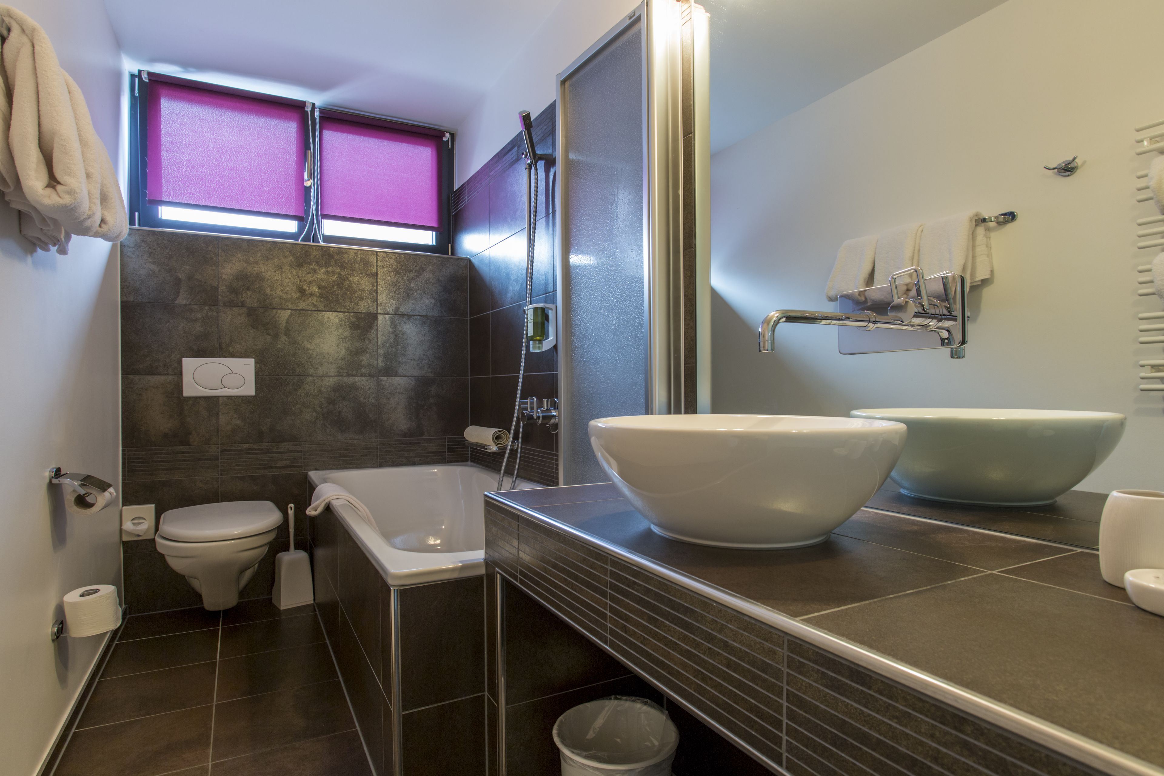 A modern bathroom with a bathtub, two large sinks, a toilet, and a shower.