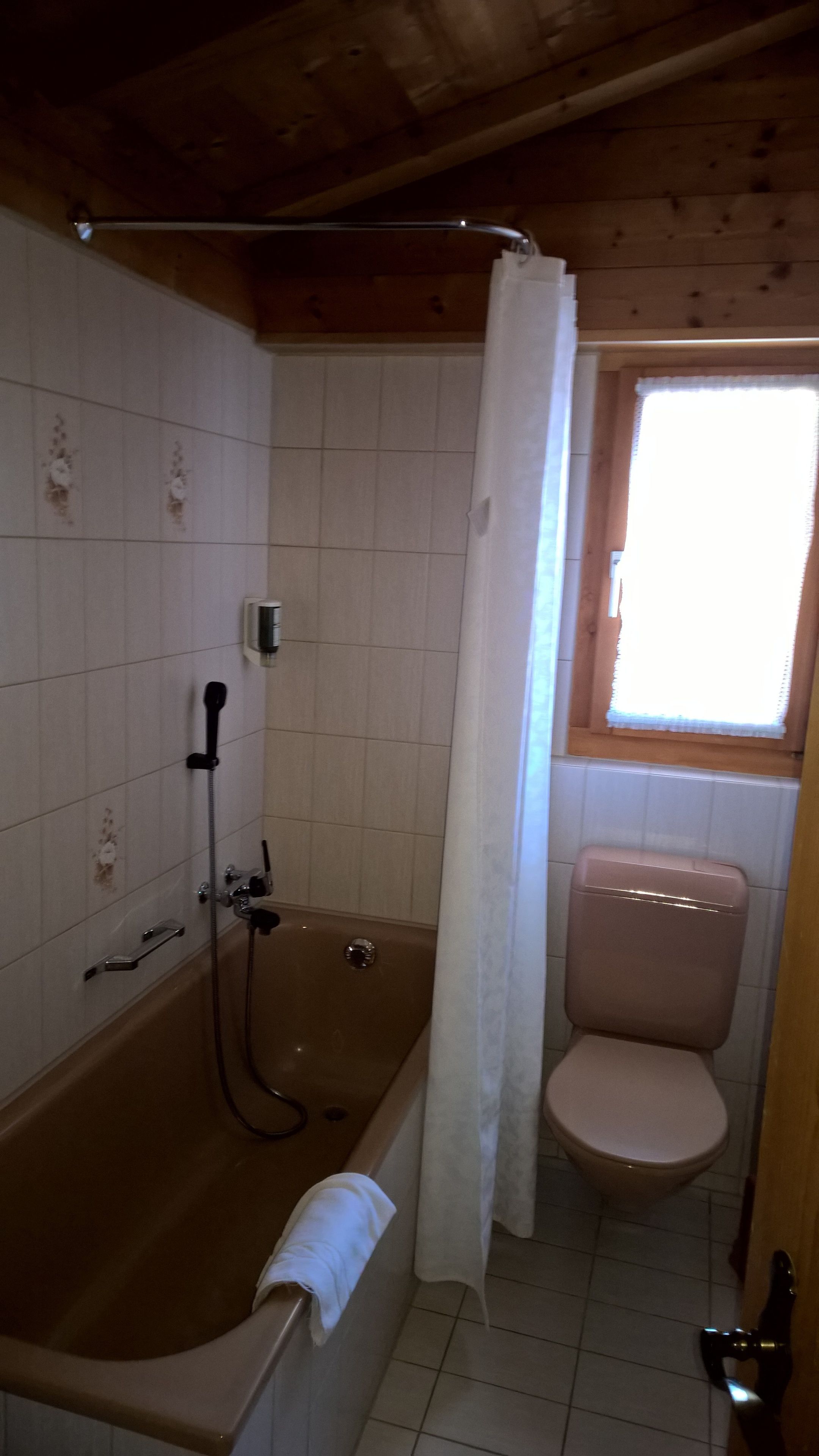 A bathroom with a bathtub, toilet, and a window.