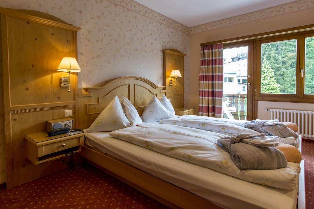 Un lit bien fait, avec des oreillers et une couverture, une table de chevet avec une lampe et une fenêtre avec des rideaux.