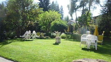 A well-maintained garden with a lawn, outdoor seating area, and a stone fountain.