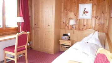 Une pièce en bois comprenant un lit, un bureau, une chaise, une armoire et une table de chevet avec une lampe.