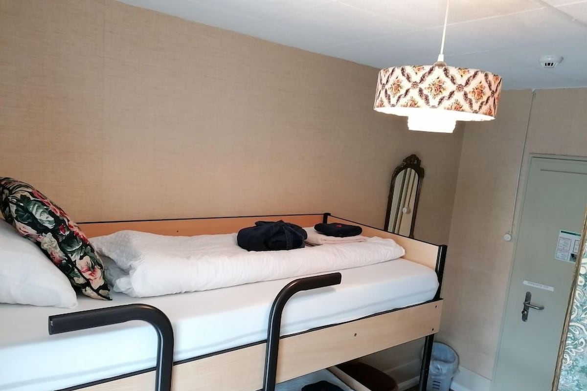 A bunk bed with a headboard, a bedside table, and a hanging light fixture.