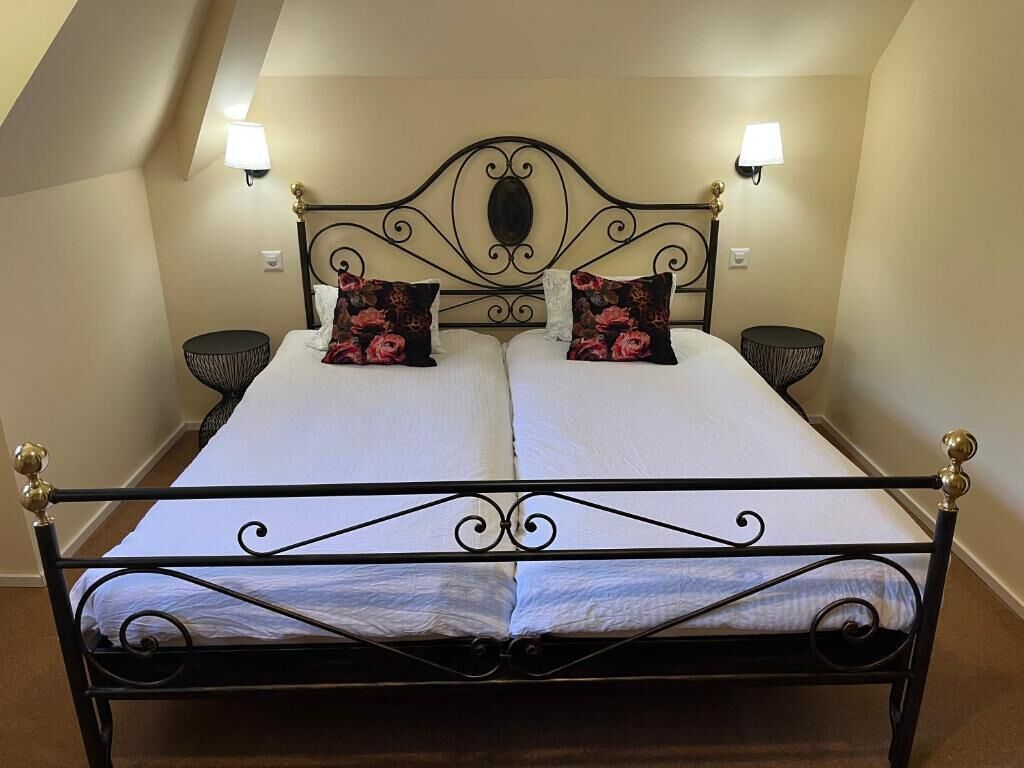 A double bed with a wrought iron frame, two wall-mounted lamps, and a decorative headboard.