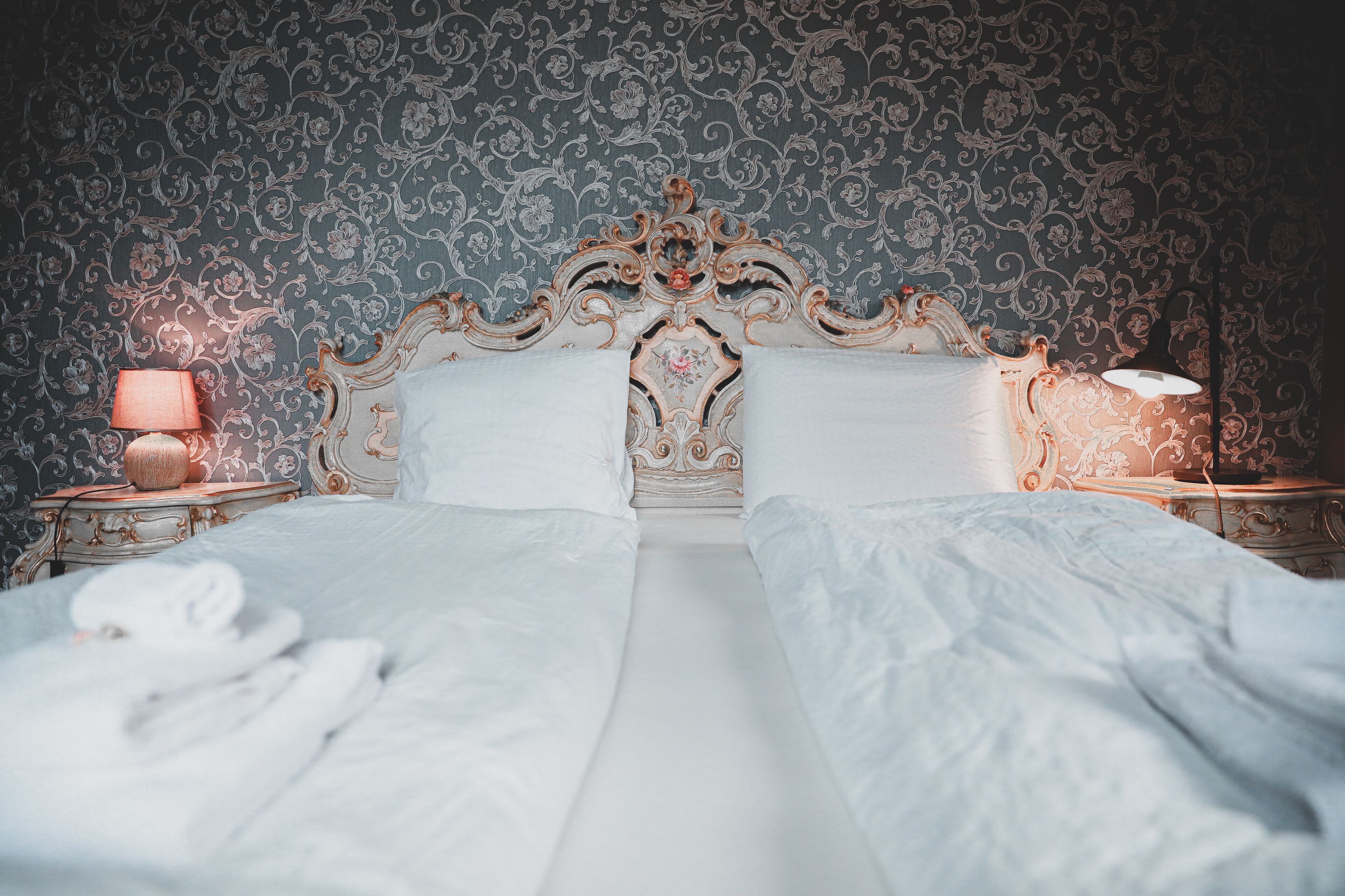 A bed with white linens, a decorative headboard, and two bedside lamps.