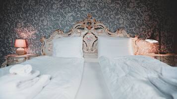 A bed with white linens, a decorative headboard, and two bedside lamps.