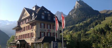 A hotel with a traditional European architectural style, featuring a prominent entrance, multiple windows, and flags.