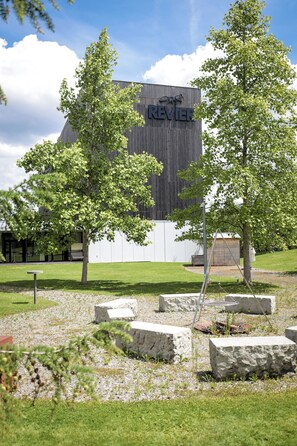 A modern building with a prominent sign, surrounded by a landscaped area with trees and stone planters.