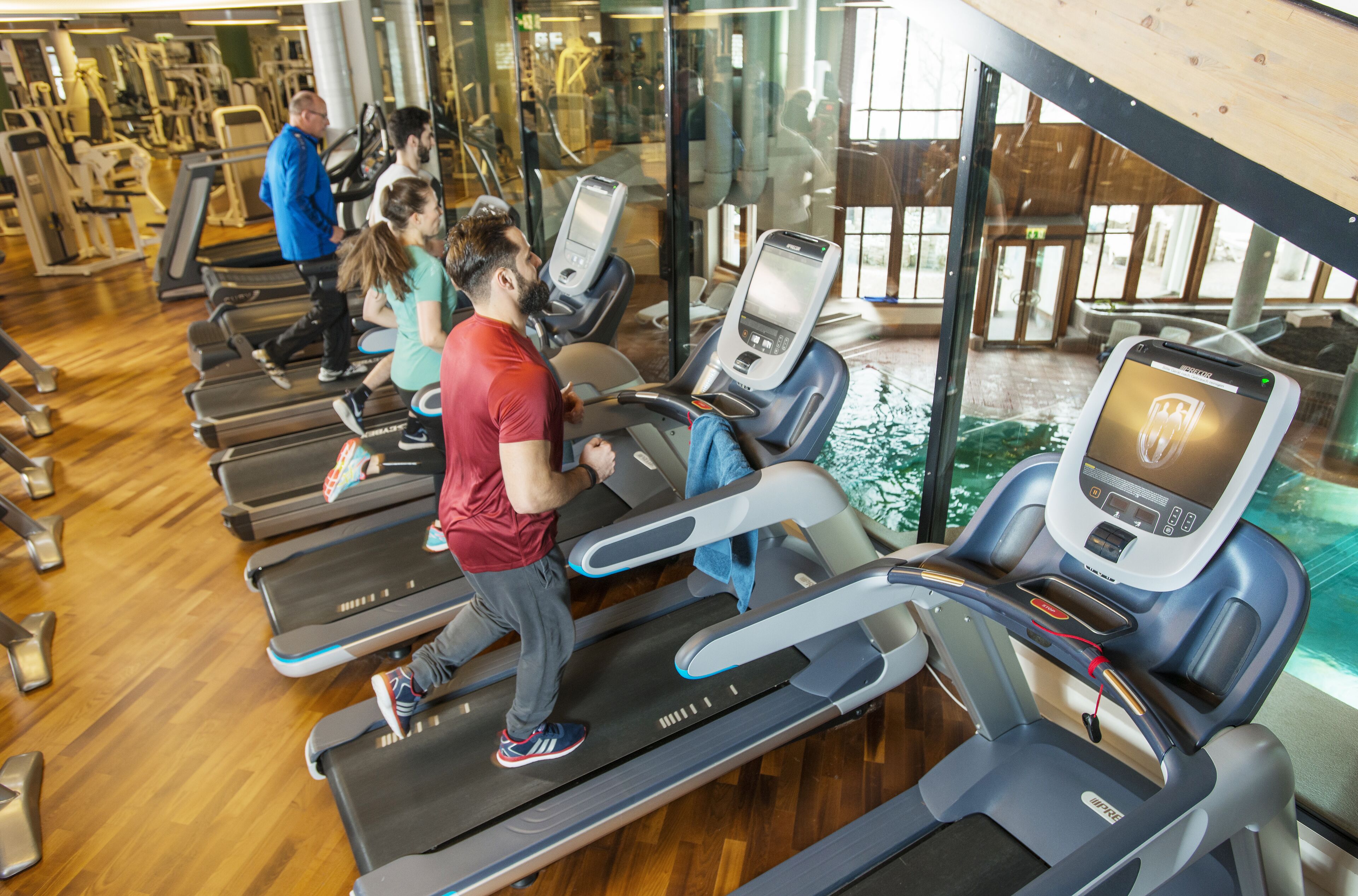 Une salle de sport équipée de tapis de course, d’appareils d’exercice et dotée d’une grande fenêtre.