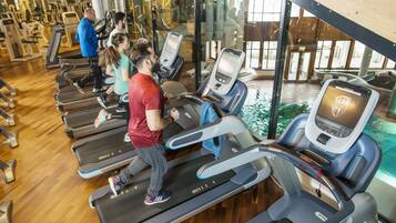 Une salle de sport équipée de tapis de course, d’appareils d’exercice et dotée d’une grande fenêtre.